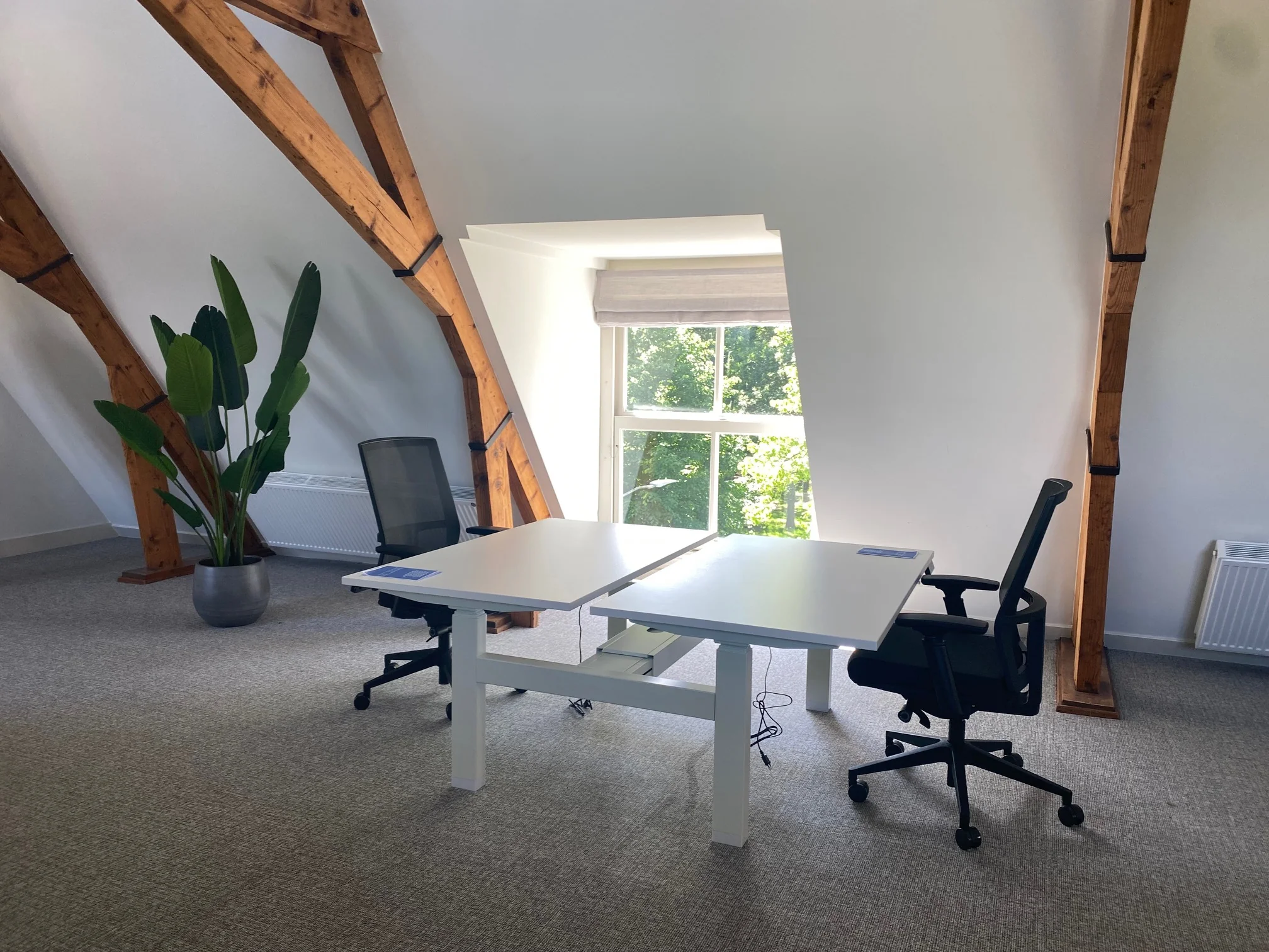 Licht en modern kantoor aan de Kleine Houtweg met twee bureaustoelen, een wit bureau en houten balken.